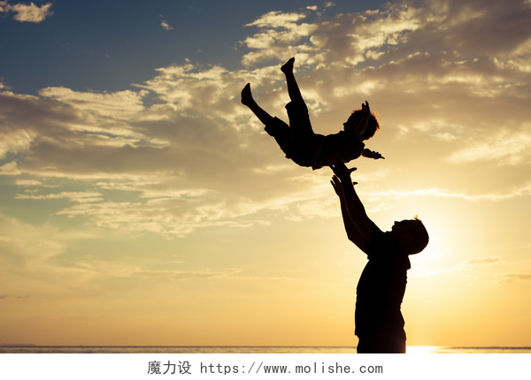 黄昏下父亲和儿子的亲子活动父亲和儿子在日落的时候在海滩上玩.